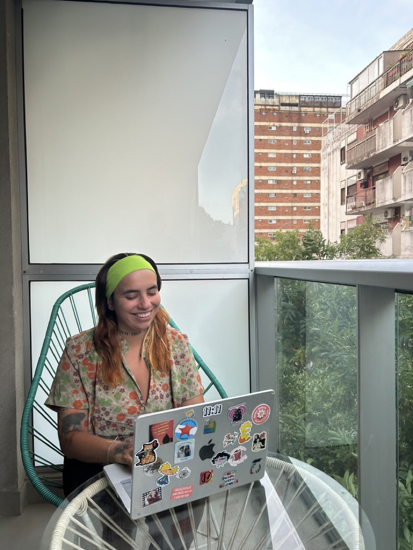 Frida trabajando en su laptop en el balcón